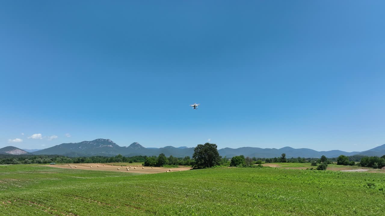 Aerial follows drone camera equipment flying above rural plantation fields in sunny daylight, recording