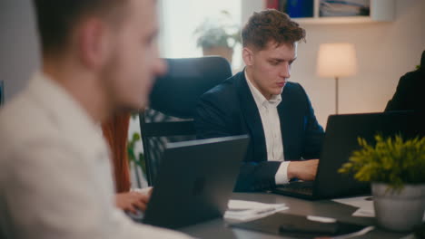 бизнесмен, работающий на ноутбуке за столом в офисе.