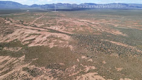 panorámica aérea de drones sobre el desierto seco australiano hasta un parque de energía eólica renovable cerca de las montañas