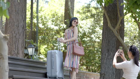 Happy-asian-female-friends-with-suitcase-doing-selfie-on-stairs-of-home-on-sunny-day,-slow-motion