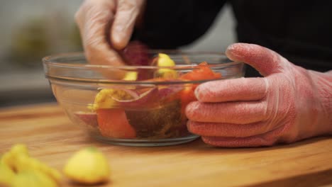 mixing the fresh cut vegetables in seasoning. the mix includes bell peppers, squash and an array of aromatic spices.