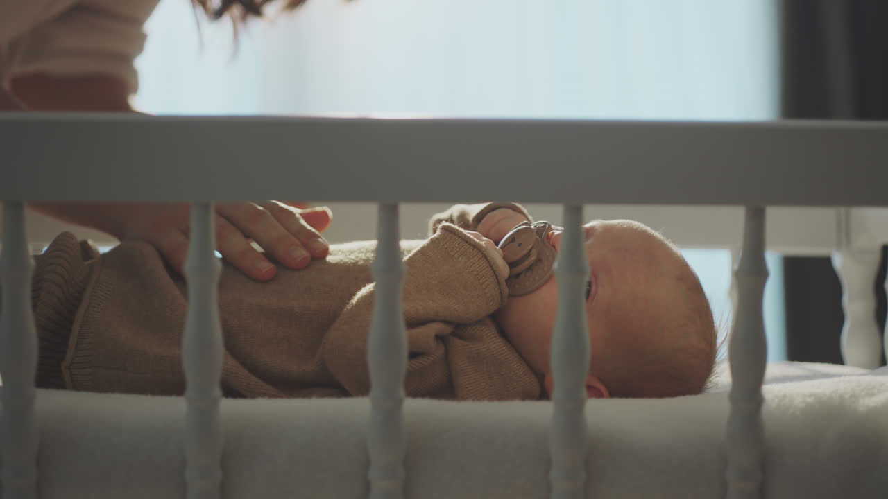 Baby in crib being cared for by a parent