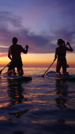 couple paddleboarding at sunset