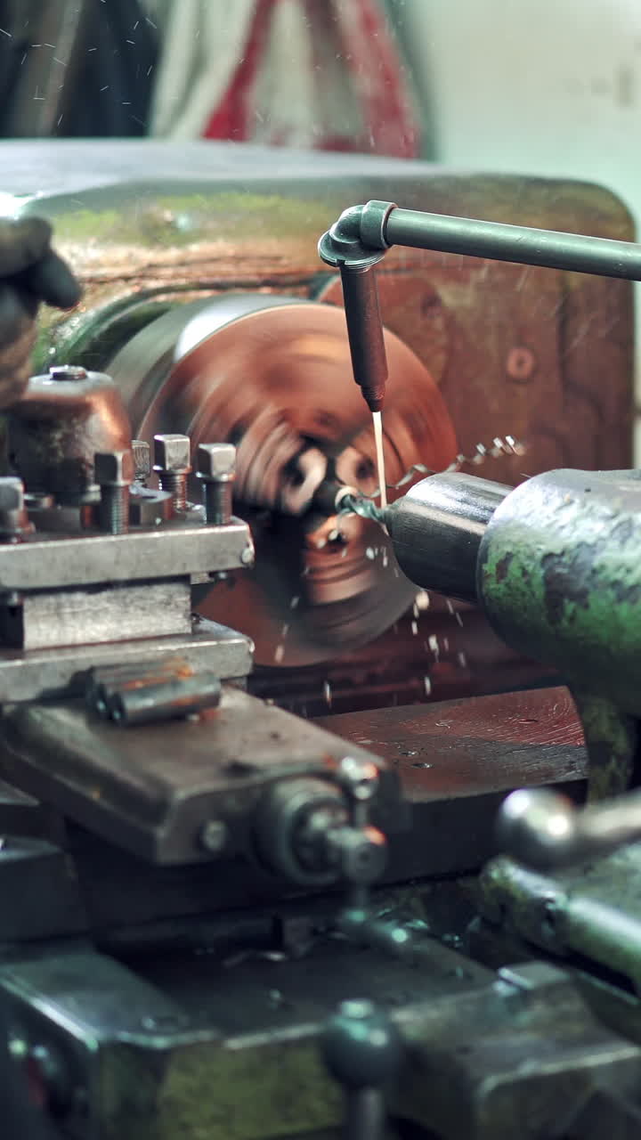 A worker controls the process of drilling a hole in a part on a lathe using coolant for cleanliness processing of surface. Close-up. Vertical video
