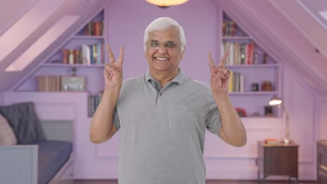 happy indian old man showing victory sign