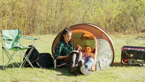 Freund-Legt-Sich-Auf-Campingzelt,-Während-Freundin-Ein-Buch-Liest