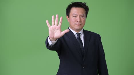 mature japanese businessman against green background