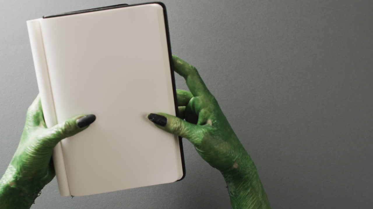 Video of halloween green monster hands and notebook with copy space on grey background
