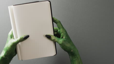 video de las manos del monstruo verde de halloween y el cuaderno con espacio de copia en fondo gris