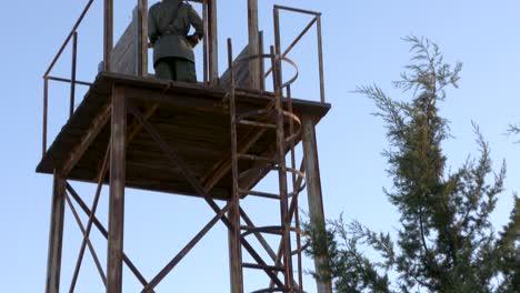 tilt up on a military watch tower to reveal an armed soldier keeping watch