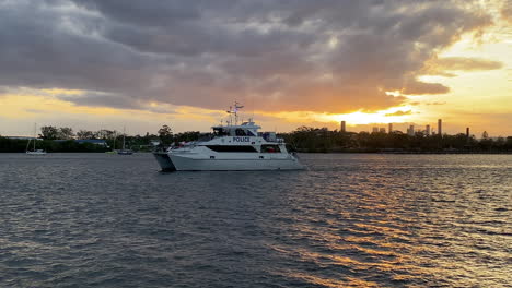 El-Barco-De-La-Policía-De-Agua-De-Queensland-Patrulla-El-Río-Brisbane-Con-Una-Puesta-De-Sol-Naranja-En-El-Fondo