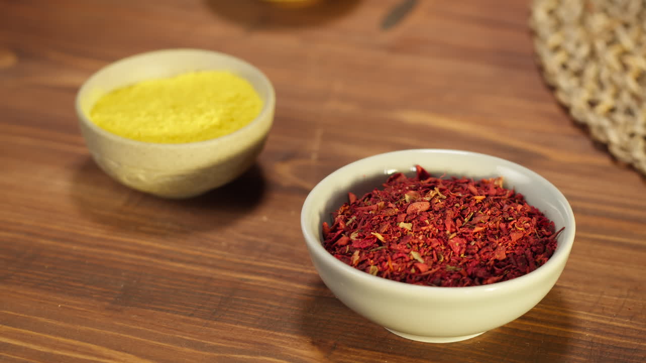 Two Bowls of Vibrant Yellow and Red Spices on a Wooden Table