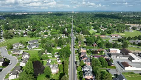 peaceful and charing houses area with straight street surrounded by green trees in summer. american suburb district with single family houses and homes. aerial wide shot.