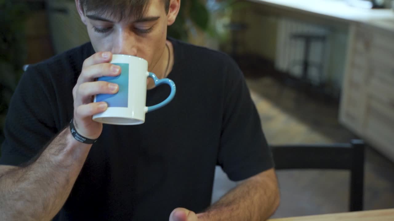 joven estudiante europeo está disfrutando de su café o té en la cafetería con fondo natural