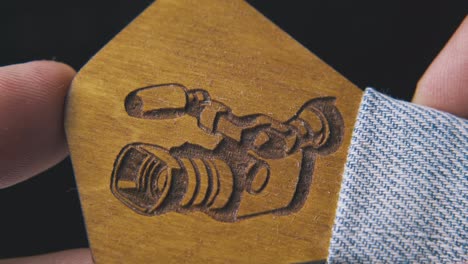 man-shows-wooden-bow-tie-with-camera-on-dark-background