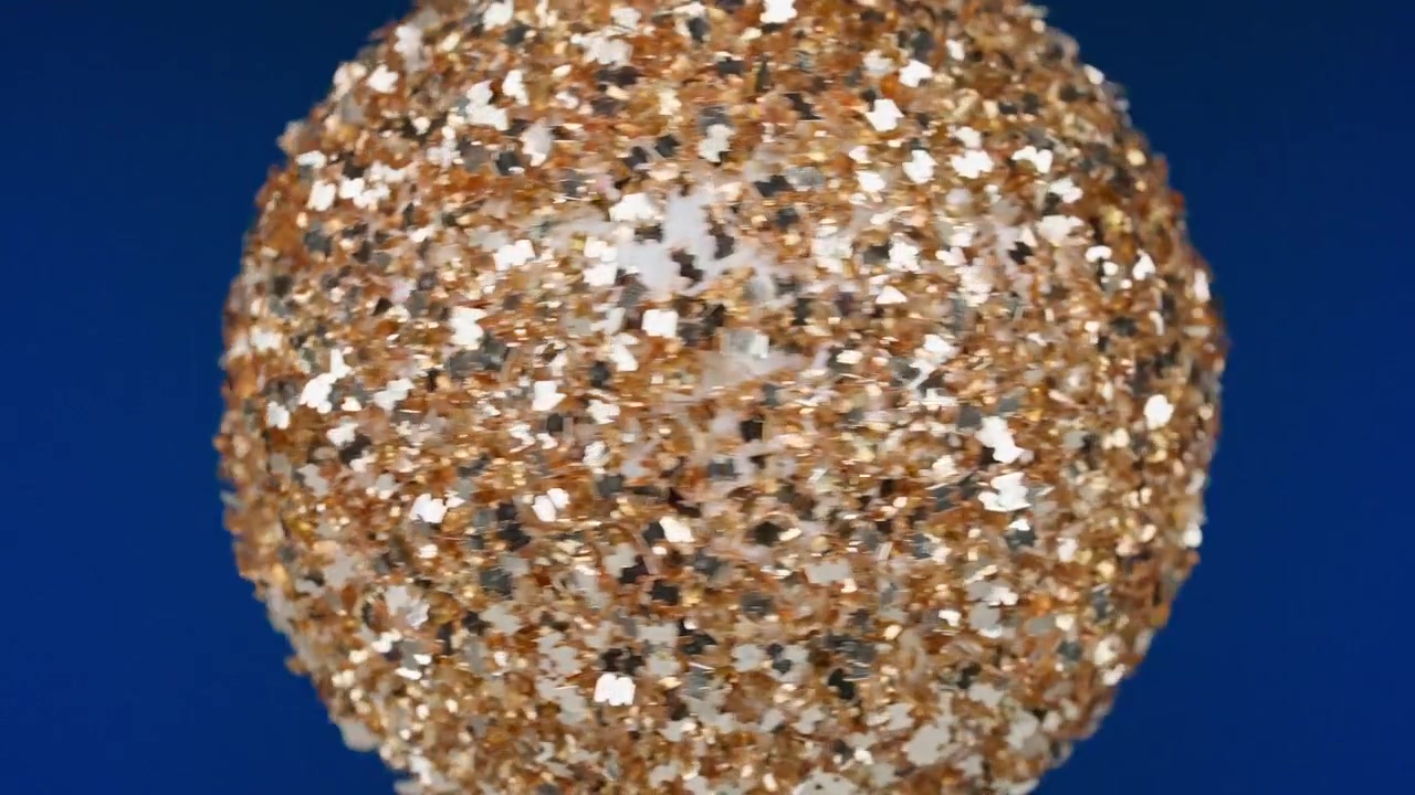 Palla glitterata oro e argento rotante su sfondo blu