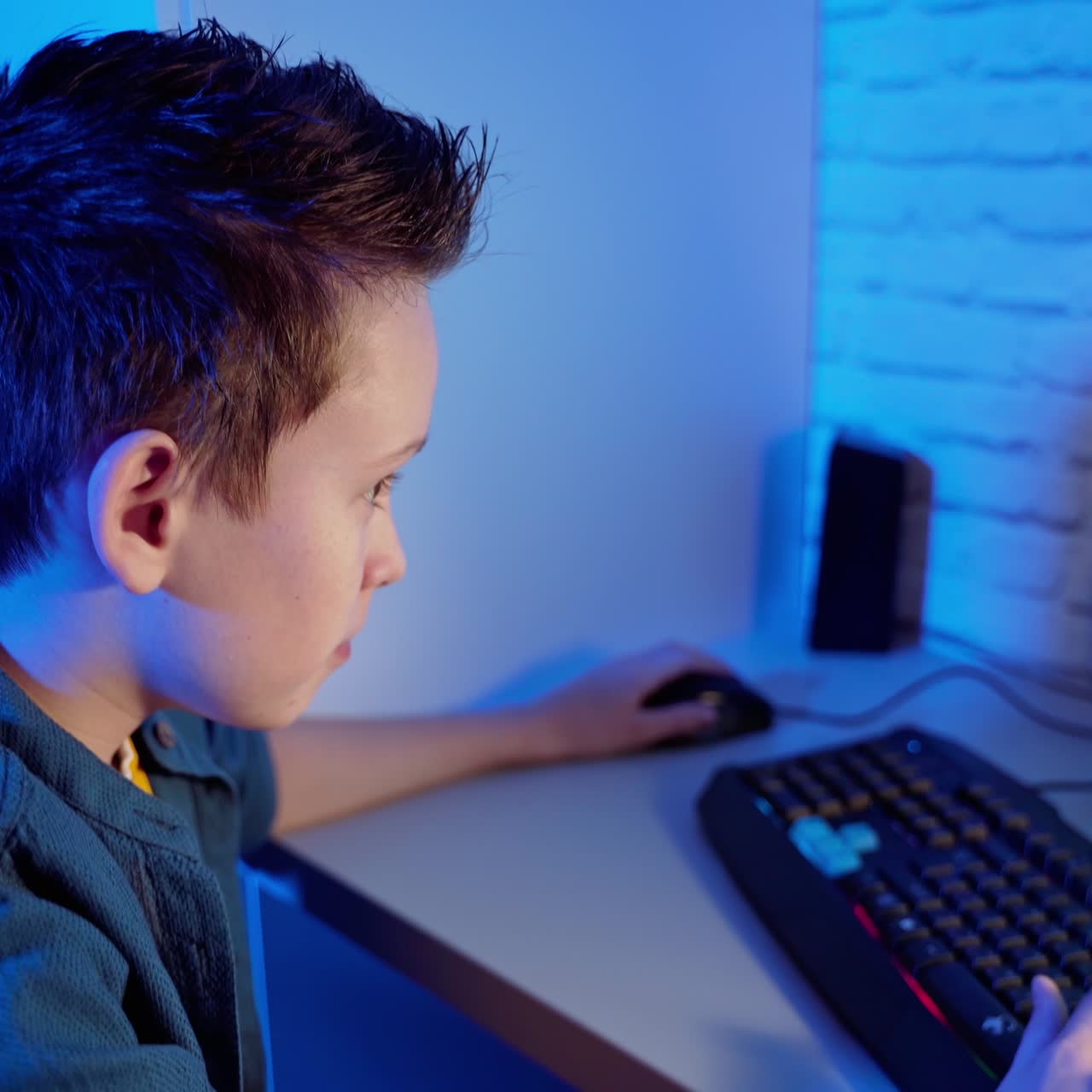 Boy playing computer game at home. Teenager sitting in front of the screen concentrated on virtual reality of the game in the room.