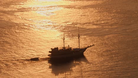 silhouette of sailing ship navigating in open sea at sunset