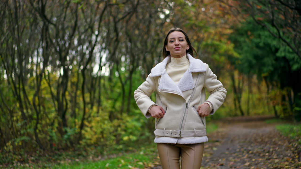 Attractive Caucasian lady running in the park. Beautiful lady with long hair spending time in autumn nature. Blurred backdrop.