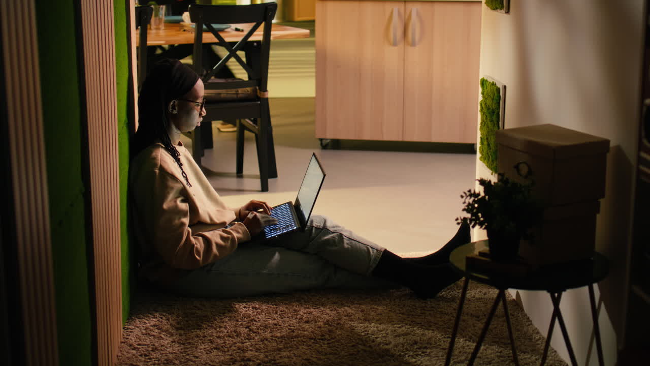 Black female adult, browsing on laptop, cozy moment, on floor hallway