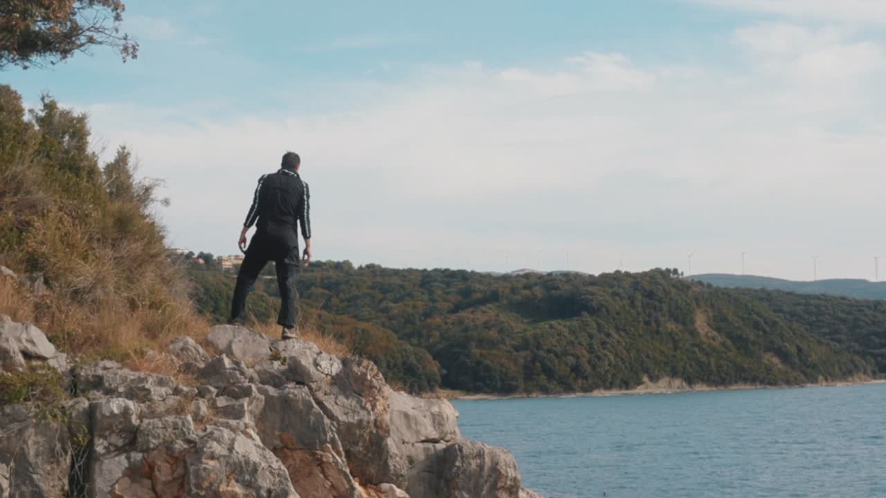 hombre de pie en un acantilado con vistas al mar