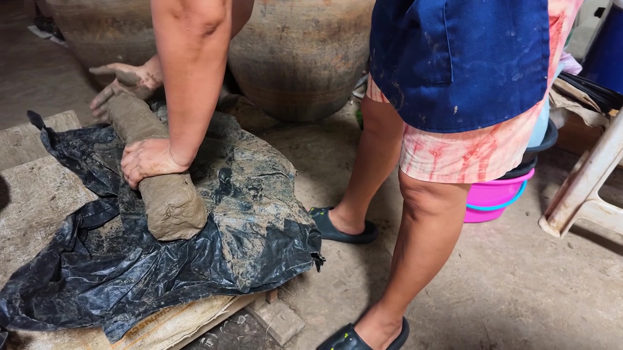 A Thai artisan rolls and shapes raw clay in a traditional workshop on Koh Kret.