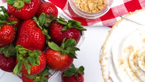 panning across a strawberry shortcake martini cocktail with fresh red strawberries, crushed graham cracker, whipped cream and sweet honey on a white plate. mixing up a strawberry dessert cocktail.