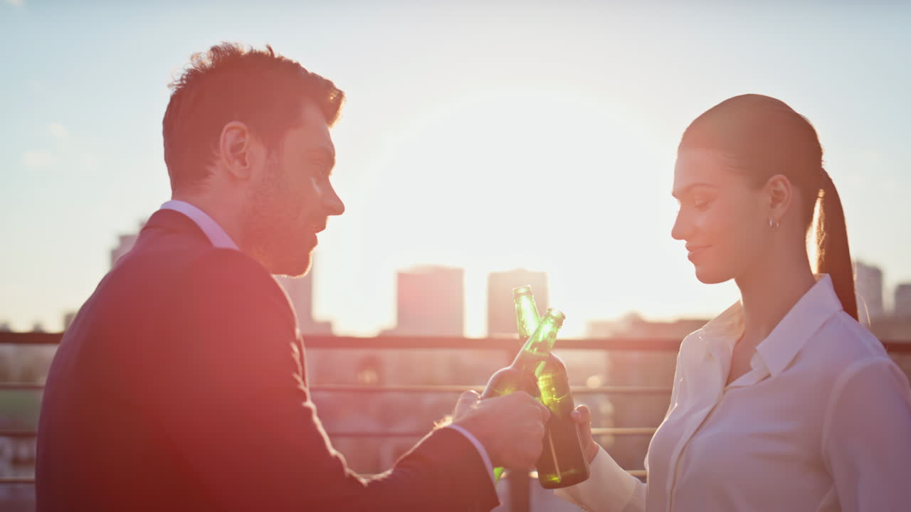 Woman man clinking bottles beer enjoying sunset on balcony closeup