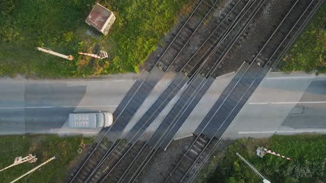 Aerial-Top-Down-View-of-Passenger-Cars-Crossing-Railway-Crossing-on-Asphalt-road