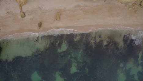 Aerial-top-down-view-dolly-across-Algarve-Benagil-caves,-Portugal-transparent-ocean-coastline