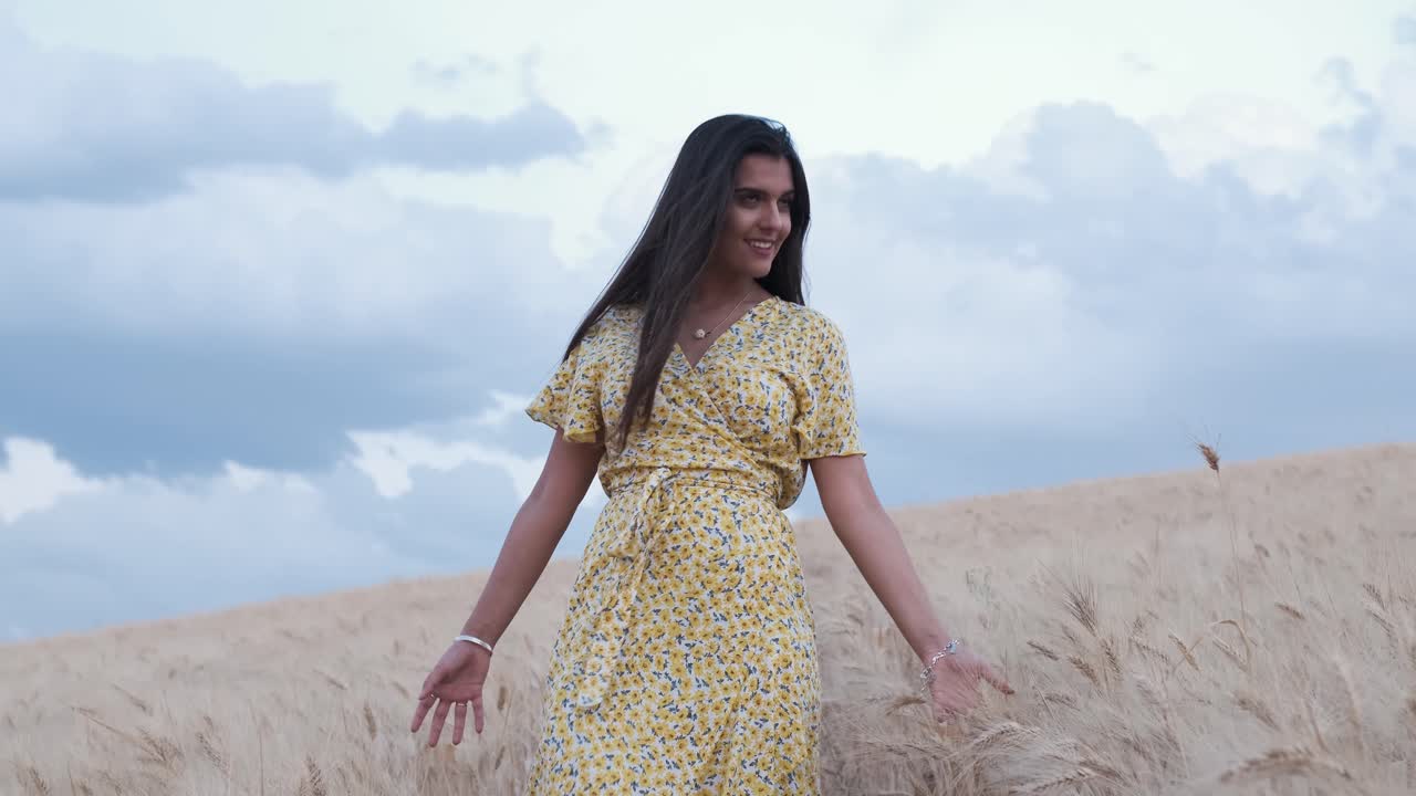Front view of a hispanic young woman while walking through the field.