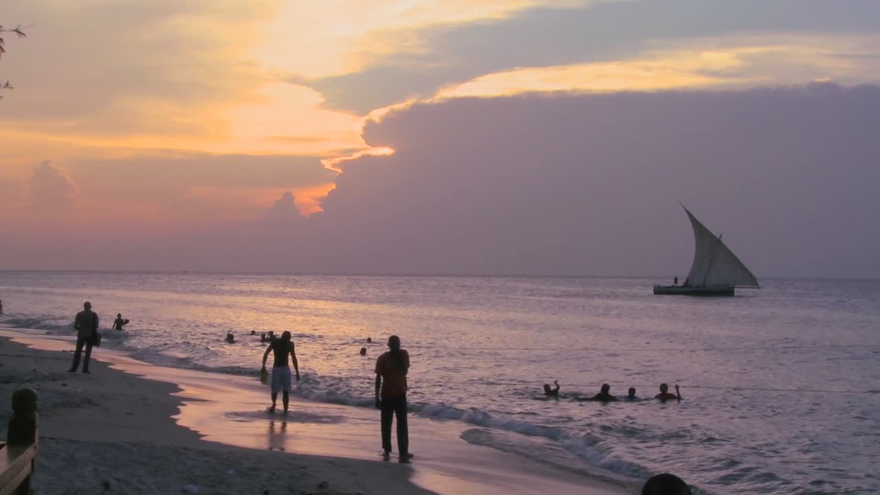 un velero dhow navega a lo largo de la playa en stone town zanzíbar al atardecer