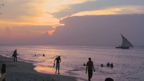 Ein-Dhau-Segelboot-Segelt-Bei-Sonnenuntergang-Am-Strand-Von-Stone-Town-Sansibar-Entlang