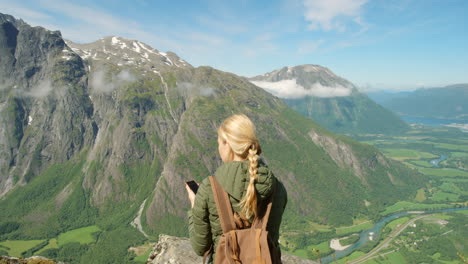 woman taking pictures of scenic norwegian mountain landscape