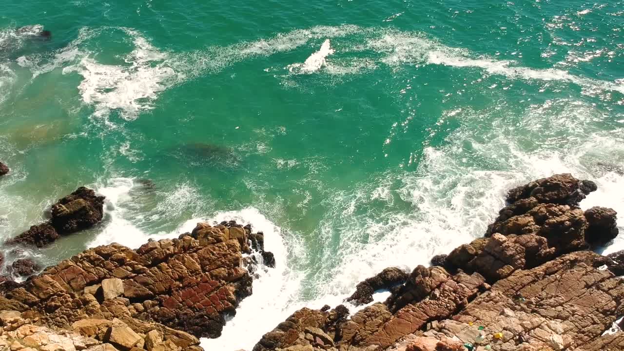 costa rocosa con olas turquesas rompiendo en rocas, vista aérea de drones