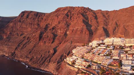 Setting-sun-casts-red-glow-on-white-houses-of-Los-Gigantes,-Tenerife