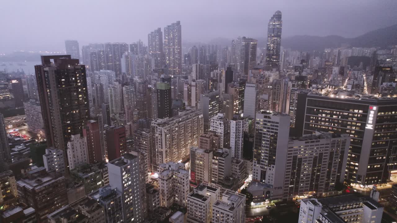 Iluminação noturna em um famoso distrito de Kowloon, chuvoso e nublado, paisagem urbana aérea panorâmica 4k de Hong Kong.