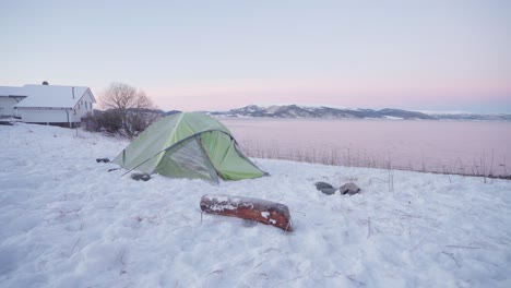 camper's tent and a piece of wood log on snow by the lakeshore