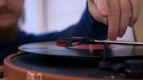 close-up of a man putting a vinyl record into a turntable, the record starts spinning and a needle is slowly lowered onto it to play music. vintage listening to music at home