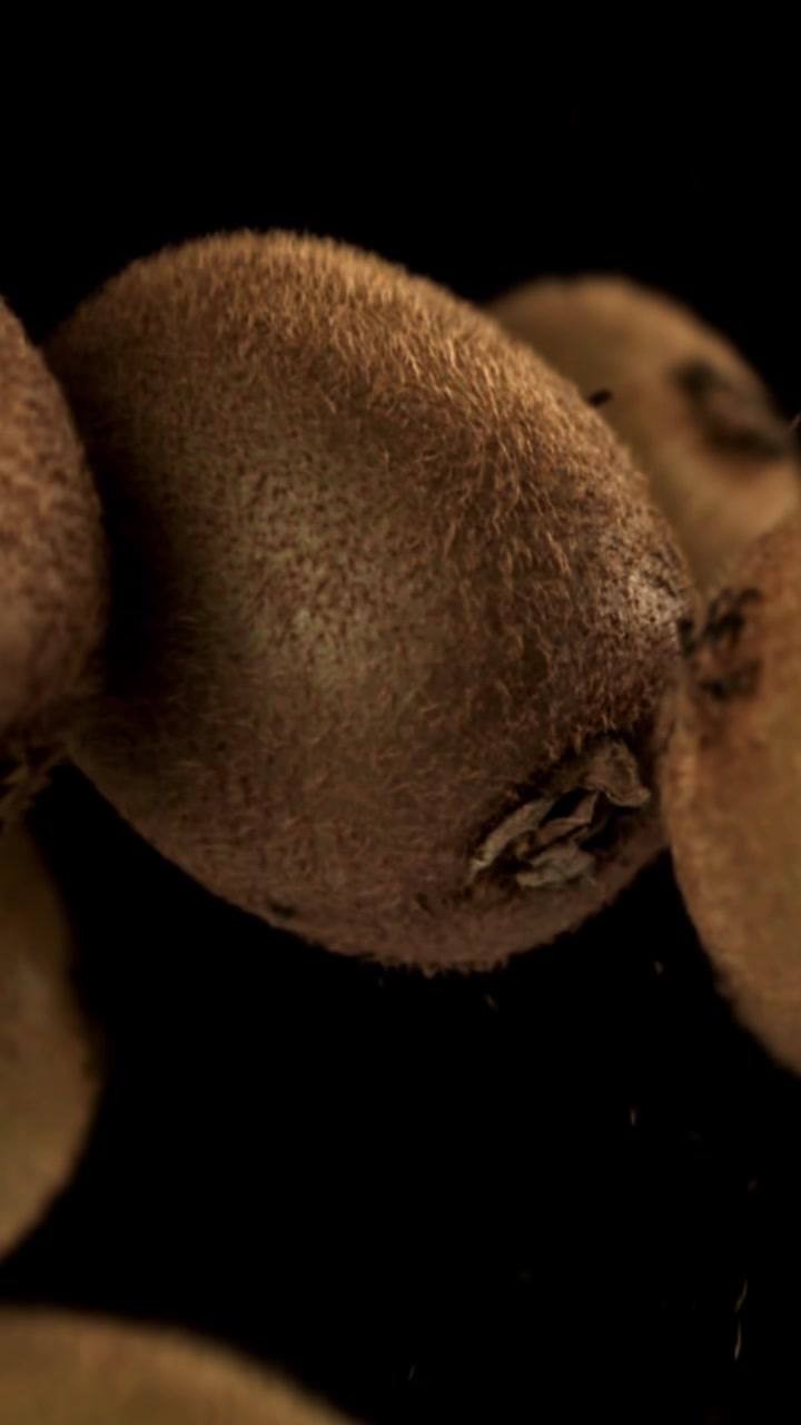 Kiwi biologici che si sollevano lentamente su sfondo nero