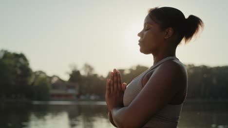 mujer afroamericana practicando ejercicios de respiración en el parque.