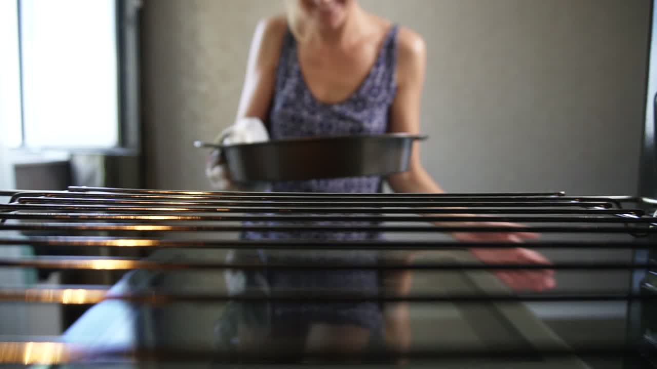 Close Up view of woman's hands taking out a baking pan from the oven. Homemade bakery