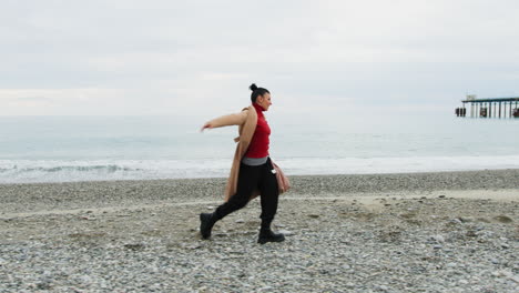 on the oceanside a woman walks dancing classical dance in energetic musical mood