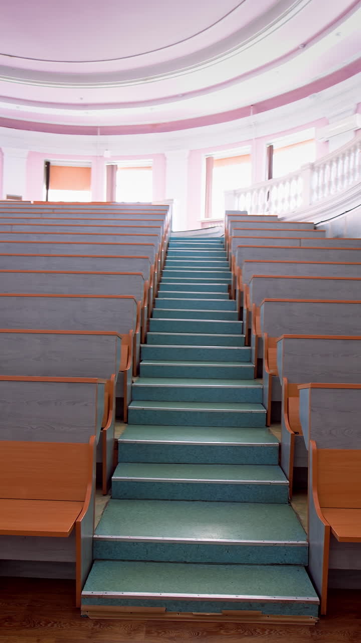 Wooden benches inside auditorium. Lecture chairs in class room with stair path in the middle of class. Vertical video