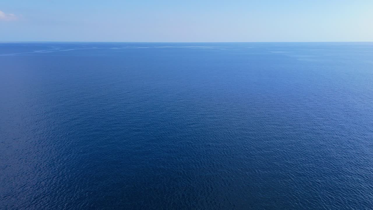 descenso aéreo panorámico a la superficie del agua del océano del mar caribe con cielo azul claro en el horizonte