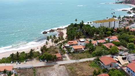 Toma-Aérea-De-Drones-En-Círculos-De-La-Pequeña-Ciudad-Costera-De-Tabatinga-Cerca-De-Joao-Pessoa-En-El-Norte-De-Brasil-Con-Pequeños-Caminos-De-Arena,-Casas-De-Playa-Y-Follaje-Tropical-En-Un-Cálido-Día-De-Verano