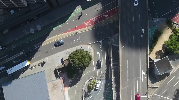 Drone top down pan across turning intersection lane in city half covered by shadow