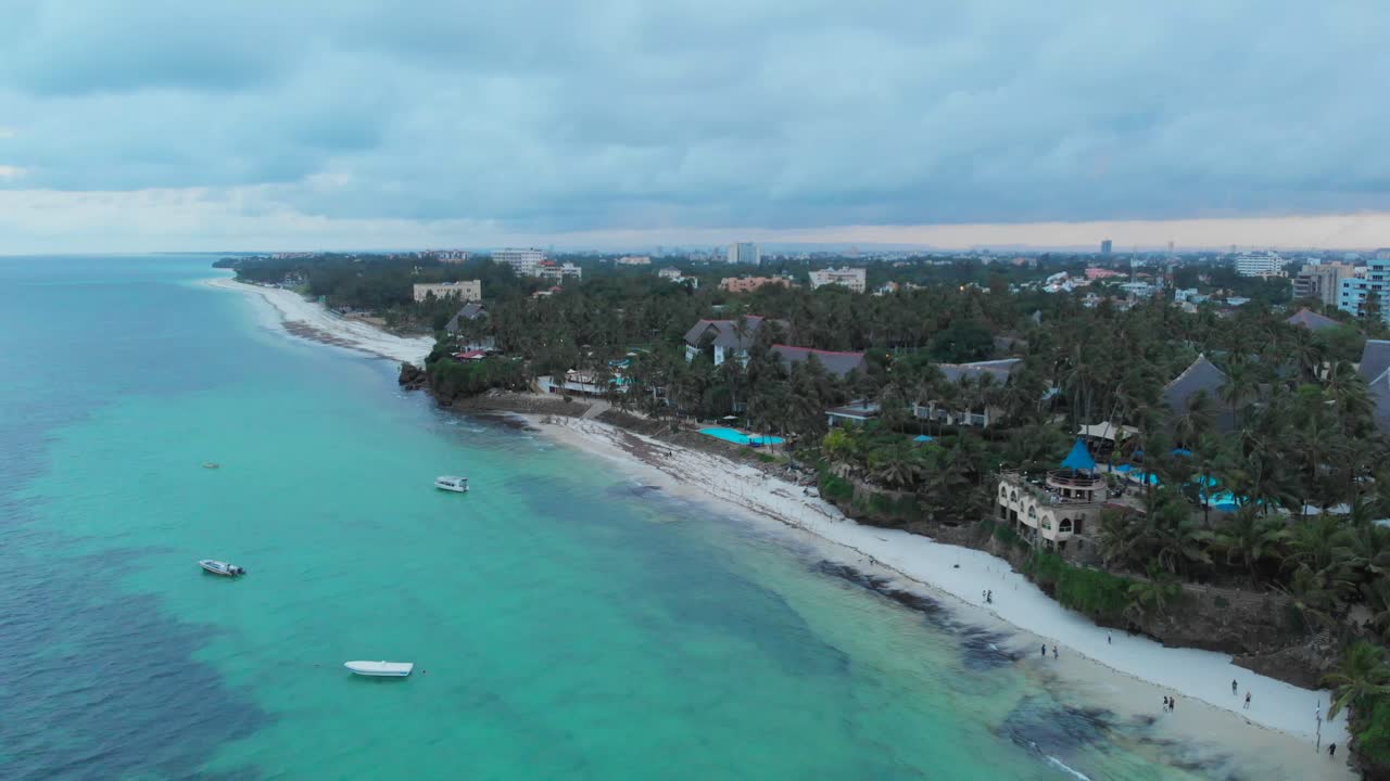 흐린 일몰 동안 몸바사 해변, 배경에 리조트