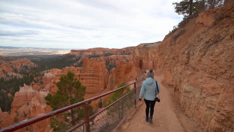 mujer caminando por un sendero de senderismo con una vista impresionante del parque nacional bryce canyon paisaje, cámara lenta, vista de atrás