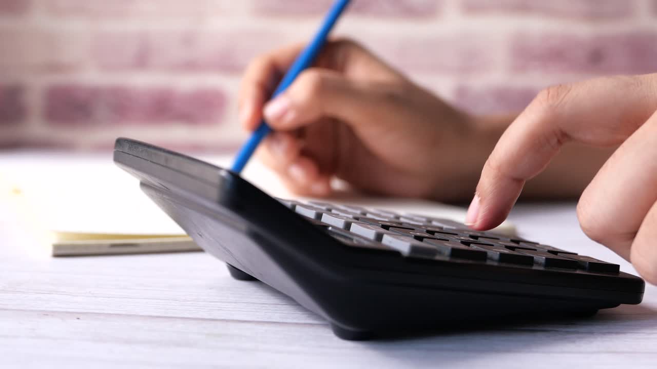 persona que utiliza una calculadora y un bloc de notas